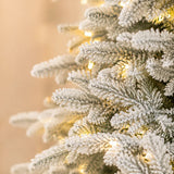 Close-up of lifelike snow-flocked branch tips and warm LED Christmas lights