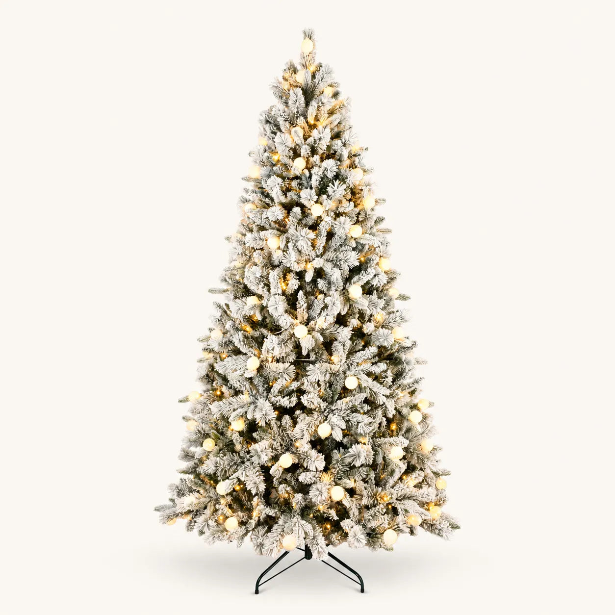 Snow-flocked pre-lit artificial Christmas tree with warm glowing globe lights